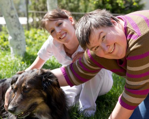 Two,Women,And,A,Half,Breed,Dog,On,A,Field